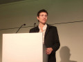 Eine kurzhaarige Referentin mit Brille spricht am Rednerpult und blickt zur Seite in Richtung Publikum.